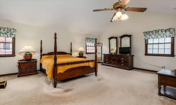 Bedroom featuring ceiling fan, light colored carpet, and lofted ceiling