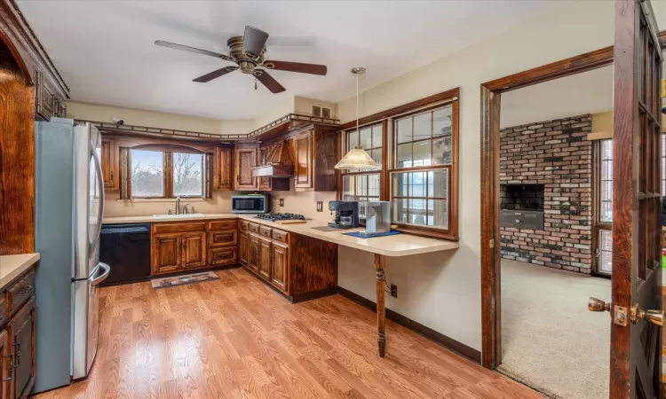 Kitchen featuring ceiling fan, sink, decorative light fixtures, light hardwood / wood-style flooring, and stainless steel appliances