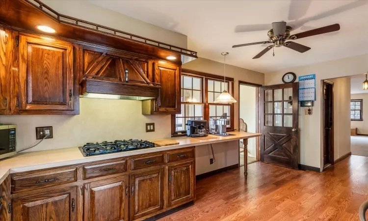 Kitchen with decorative light fixtures, ceiling fan, hardwood / wood-style floors, and black gas stovetop