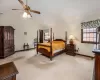 Bedroom with light colored carpet, vaulted ceiling, and ceiling fan