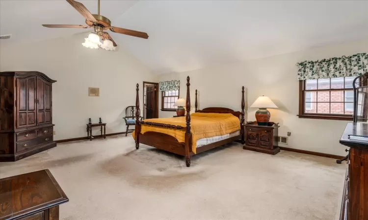 Bedroom with light colored carpet, vaulted ceiling, and ceiling fan