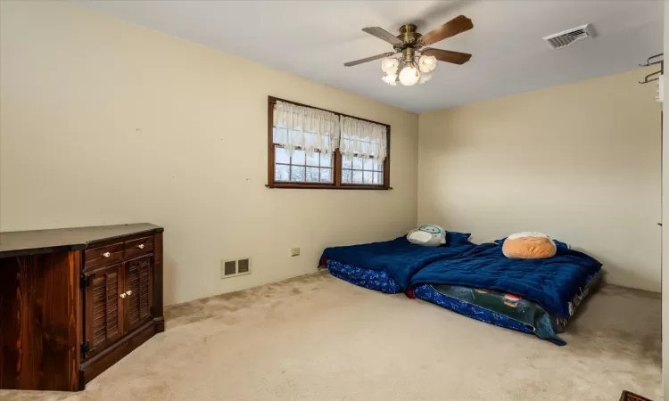 Bedroom with ceiling fan and light carpet