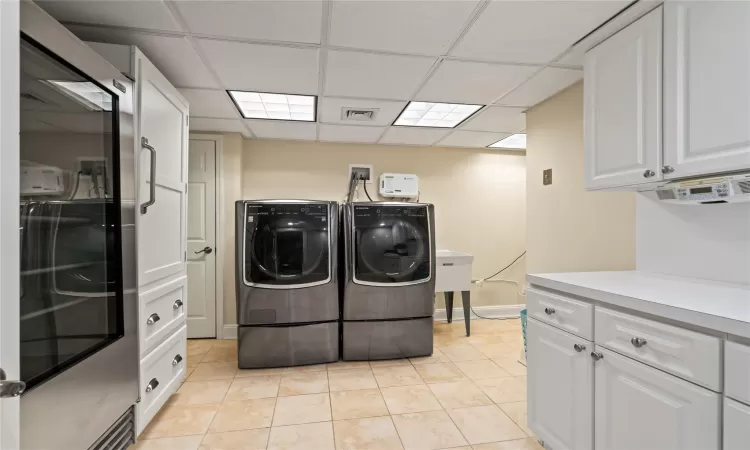 Washroom with light tile patterned floors, separate washer and dryer, and cabinets