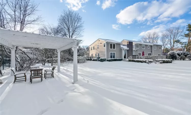 Yard layered in snow featuring a pergola