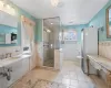 Bathroom featuring toilet, a tile shower, tile walls, tile patterned floors, and sink