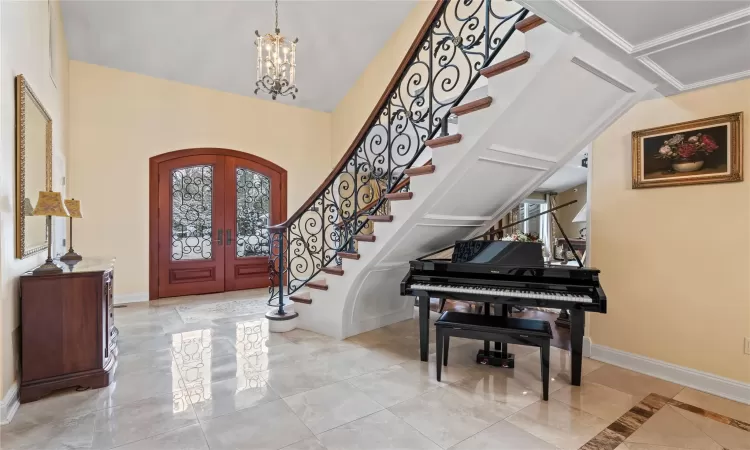 Entryway with crown molding, french doors, and a notable chandelier