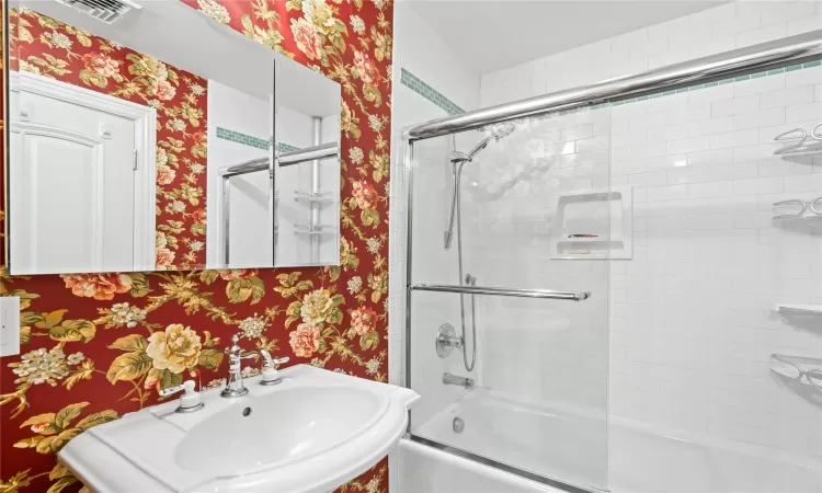 Bathroom featuring sink and shower / bath combination with glass door