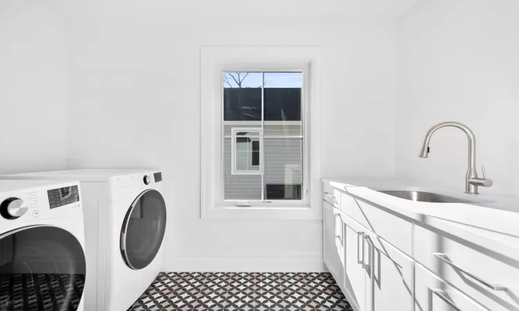 Washroom featuring sink, independent washer and dryer, and cabinets