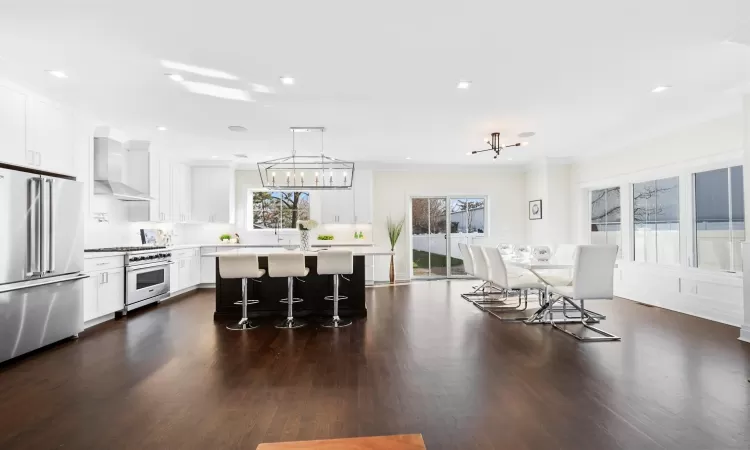 Kitchen with a kitchen island, high end appliances, a breakfast bar area, and white cabinetry