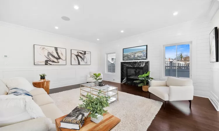 Living room featuring dark hardwood / wood-style flooring, crown molding, and a premium fireplace