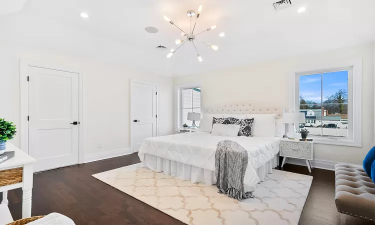 Bedroom with multiple windows, dark hardwood / wood-style floors, and an inviting chandelier