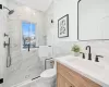 Bathroom with vanity, toilet, tile walls, and a shower with shower door