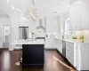 Kitchen with sink, white cabinets, a center island, wall chimney range hood, and stainless steel appliances