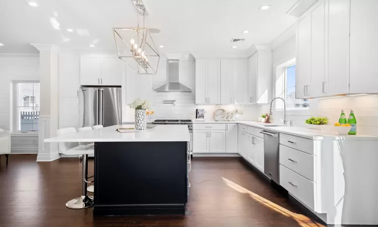 Kitchen with sink, white cabinets, a center island, wall chimney range hood, and stainless steel appliances