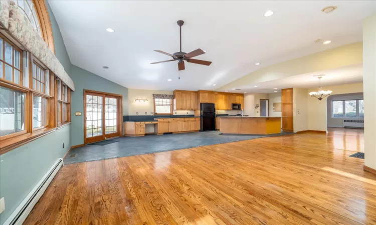 Kitchen featuring radiator heating unit, black appliances, a baseboard heating unit, kitchen peninsula, and light wood-type flooring