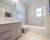 Full bathroom featuring toilet, tiled shower / bath, vanity, and tile walls