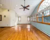 Unfurnished living room featuring ceiling fan, high vaulted ceiling, hardwood / wood-style floors, and a baseboard radiator