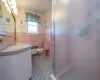 Bathroom with radiator heating unit, a shower with door, tile walls, toilet, and vanity