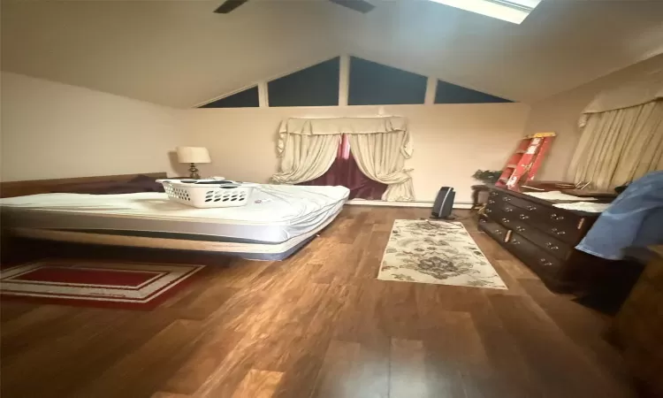 Bedroom with ceiling fan, dark hardwood / wood-style flooring, and lofted ceiling