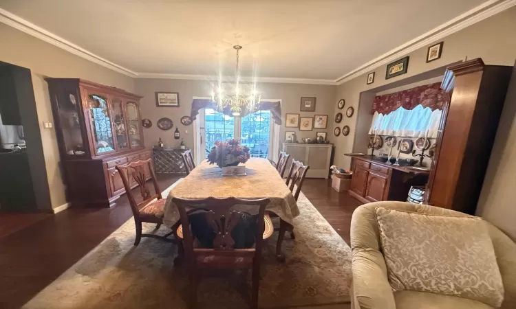 Dining room featuring crown molding, an inviting chandelier, and dark hardwood / wood-style floors