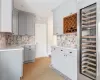 Kitchen with sink, wine cooler, backsplash, and gray cabinets