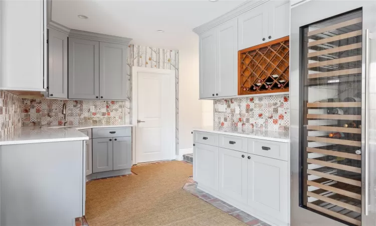 Kitchen with sink, wine cooler, backsplash, and gray cabinets