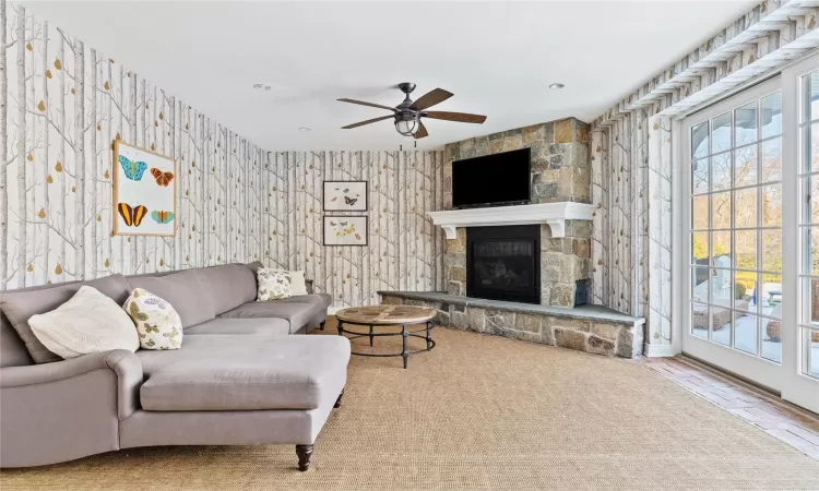 Living room featuring ceiling fan and a stone fireplace