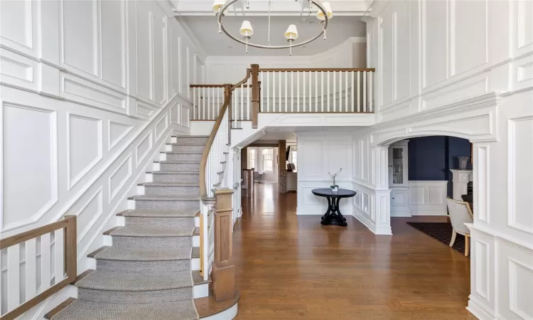 Entrance foyer with a high ceiling, dark wood-type flooring, crown molding, and a chandelier