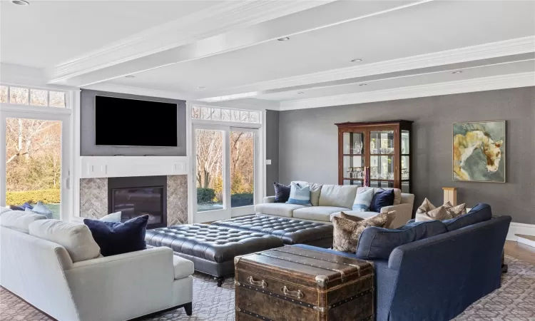 Living room featuring wood-type flooring, crown molding, and a fireplace