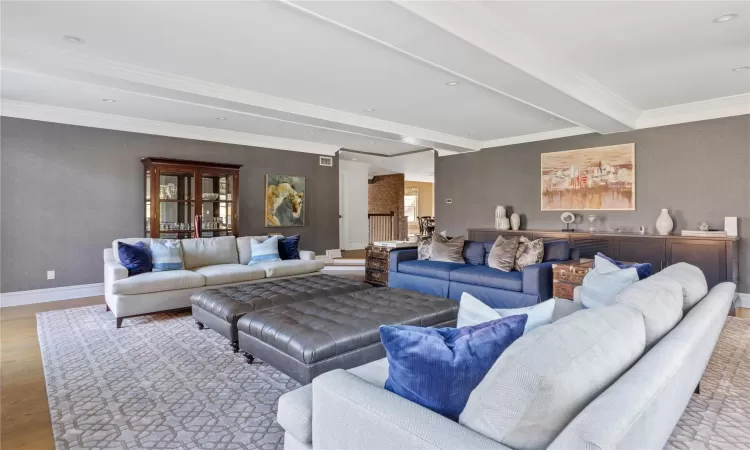 Living room featuring ornamental molding, beam ceiling, and light hardwood / wood-style floors