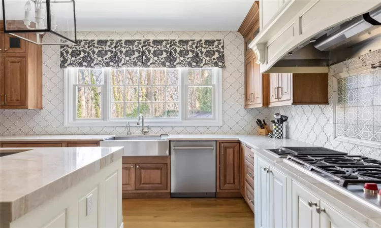 Kitchen featuring appliances with stainless steel finishes, sink, premium range hood, light wood-type flooring, and white cabinetry