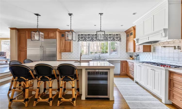 Kitchen featuring wine cooler, a kitchen bar, light hardwood / wood-style flooring, a kitchen island with sink, and appliances with stainless steel finishes