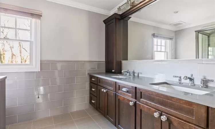 Bathroom featuring tile patterned flooring, tile walls, ornamental molding, and vanity