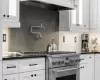 Kitchen with white cabinetry, decorative backsplash, and high end stainless steel range