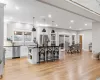 Kitchen featuring decorative light fixtures, light hardwood / wood-style floors, a kitchen island, stainless steel appliances, and white cabinets