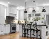 Kitchen with high end stainless steel range, premium range hood, white cabinetry, and a center island