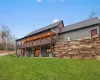 Rear view of property featuring a wooden deck and a lawn