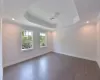 BUILDER PRIOR WORK - Spare room featuring a raised ceiling, crown molding, and dark hardwood / wood-style flooring