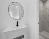 Bathroom featuring tiled shower and vanity