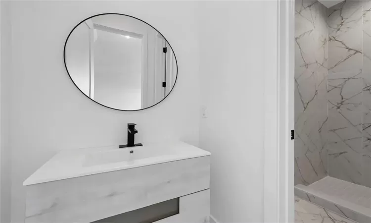 Bathroom featuring tiled shower and vanity