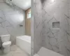 Bathroom featuring tile floors, toilet, and tile walls