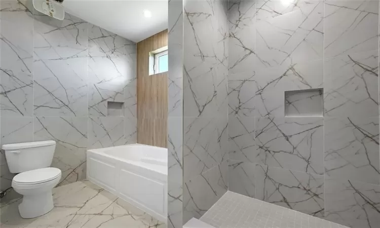 Bathroom featuring tile floors, toilet, and tile walls