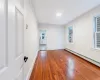 Unfurnished room featuring hardwood / wood-style flooring and a baseboard heating unit