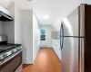 Kitchen featuring sink, light hardwood / wood-style flooring, appliances with stainless steel finishes, a baseboard radiator, and white cabinetry