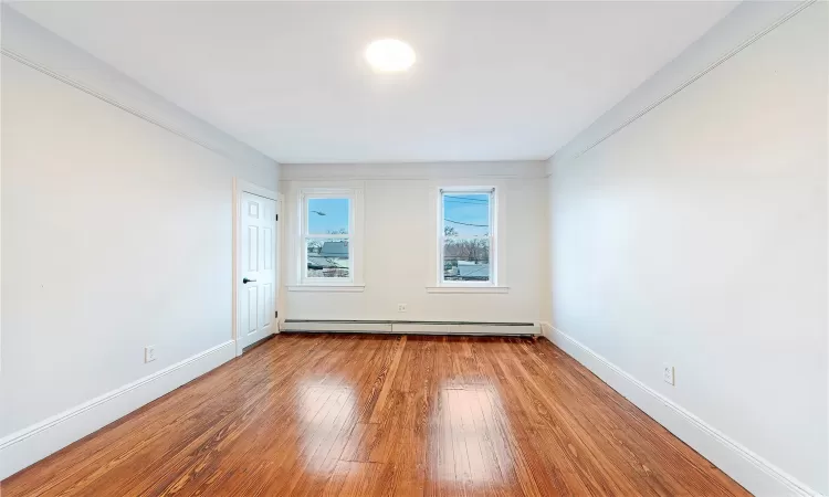 Bedroom #1 with hardwood / wood-style floors and a baseboard heating unit