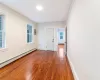 Empty room with baseboard heating, plenty of natural light, and dark wood-type flooring