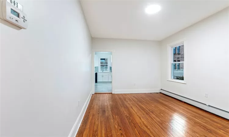 Unfurnished room featuring hardwood / wood-style flooring and a baseboard radiator