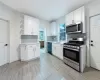 Kitchen featuring decorative backsplash, white cabinetry, sink, and stainless steel appliances