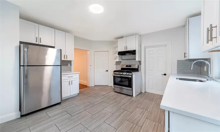 Kitchen featuring white cabinets, stainless steel appliances, tasteful backsplash, and sink