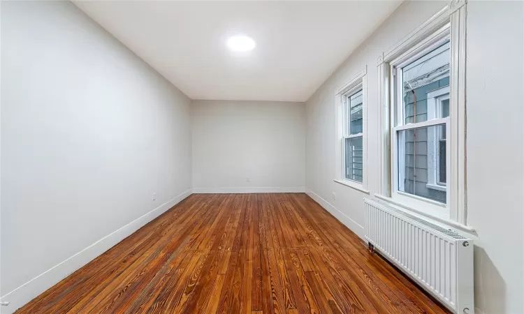 Second Angle of Unfurnished Bedroom #1 featuring dark hardwood / wood-style flooring and radiator heating unit